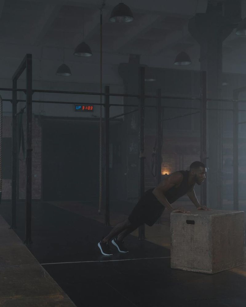 Man performing a controlled functional strength movement in a dark gym